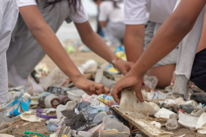 Hands cleaning waste from beach in Ecuador.